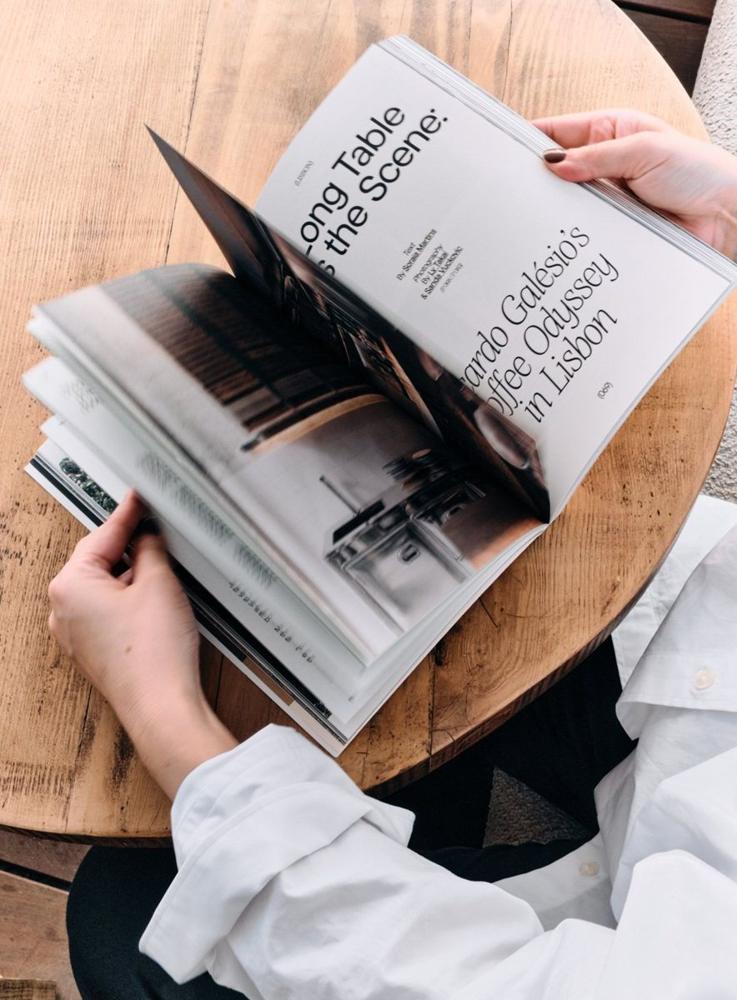 A reader turning the pages of Still. at a café table